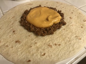 Spread cheese sauce over ground beef